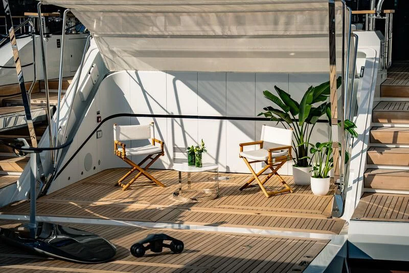 a deck with a chair and a table and a plant on the side aboard HAYAT Yacht for Sale
