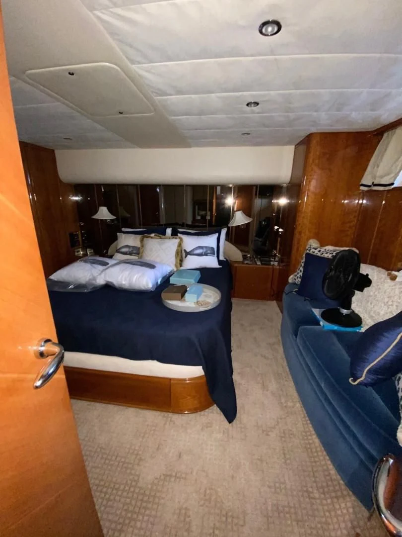 a bedroom with a bed and a blue couch aboard JOIE DU ROI Yacht for Sale