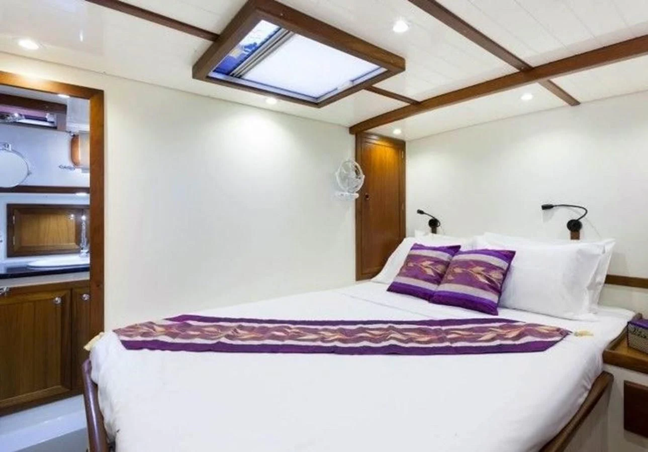 a bed with purple and white sheets aboard DALLINGHOO Yacht for Sale