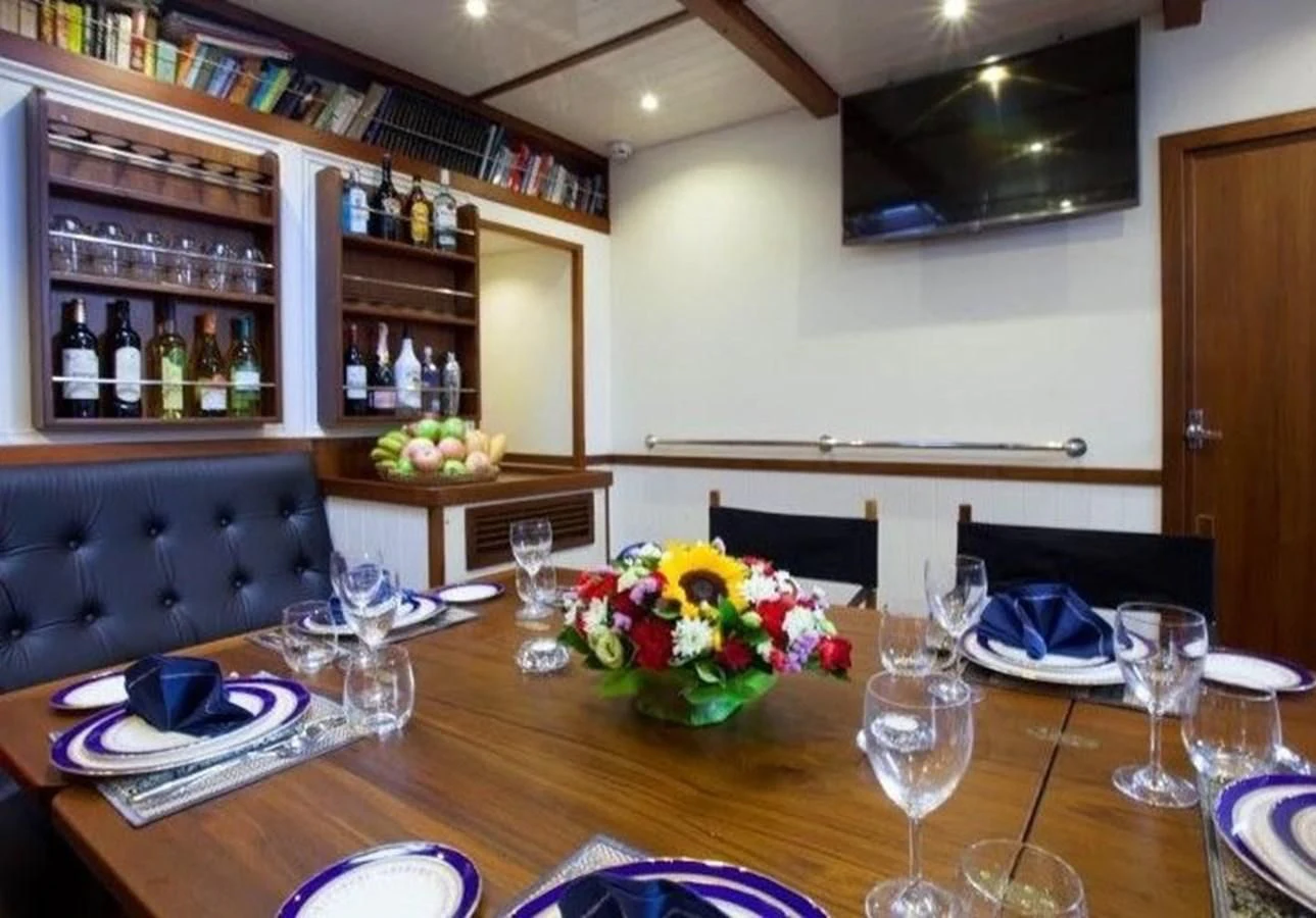 a dining room table with wine glasses and plates aboard DALLINGHOO Yacht for Sale