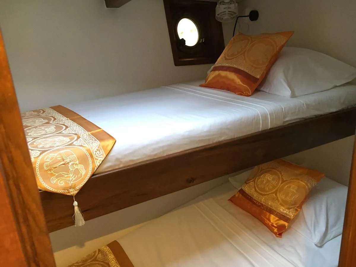 a bed with a white sheet and pillows aboard DALLINGHOO Yacht for Sale