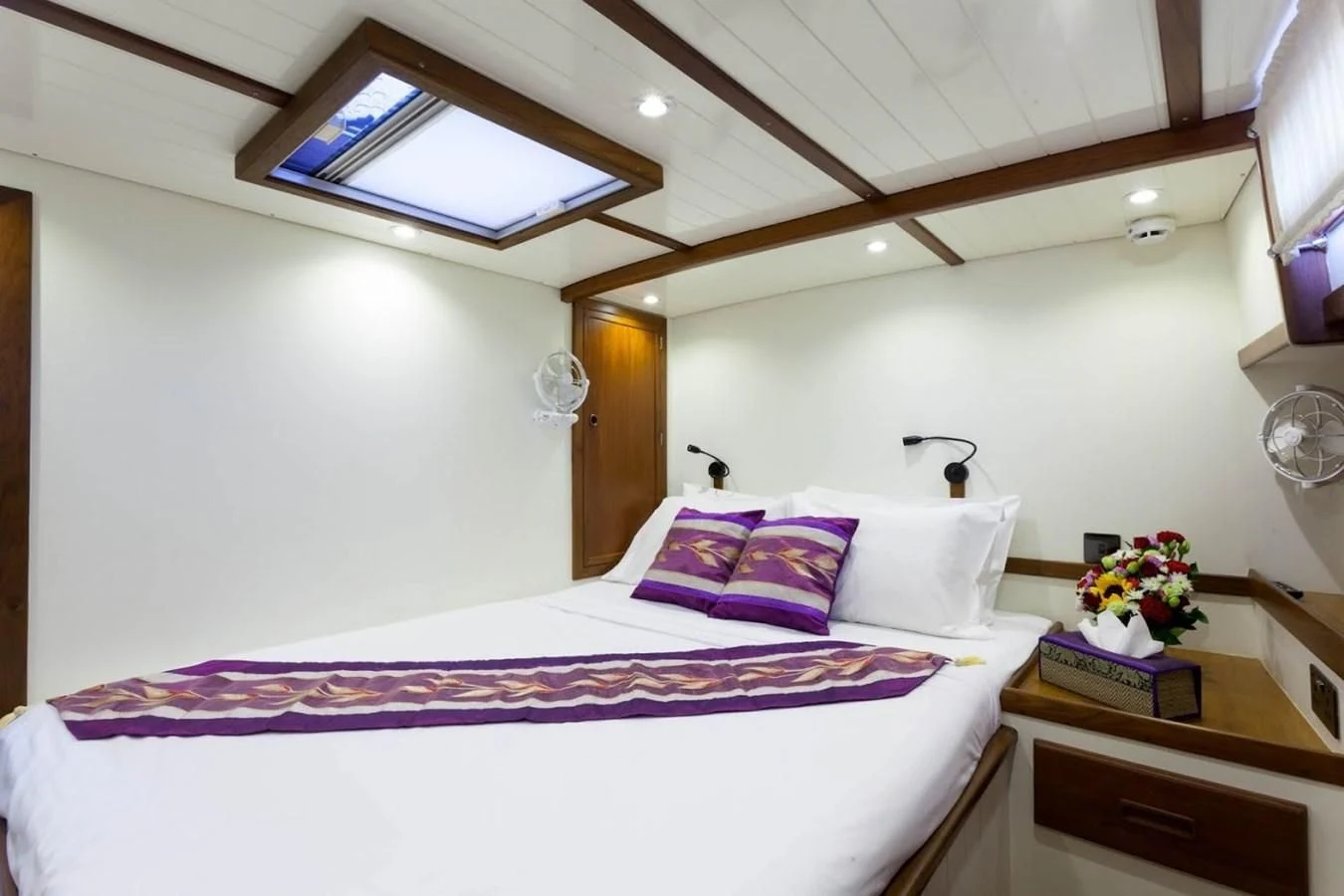 a bed with a purple and white blanket and a white pillow aboard DALLINGHOO Yacht for Sale