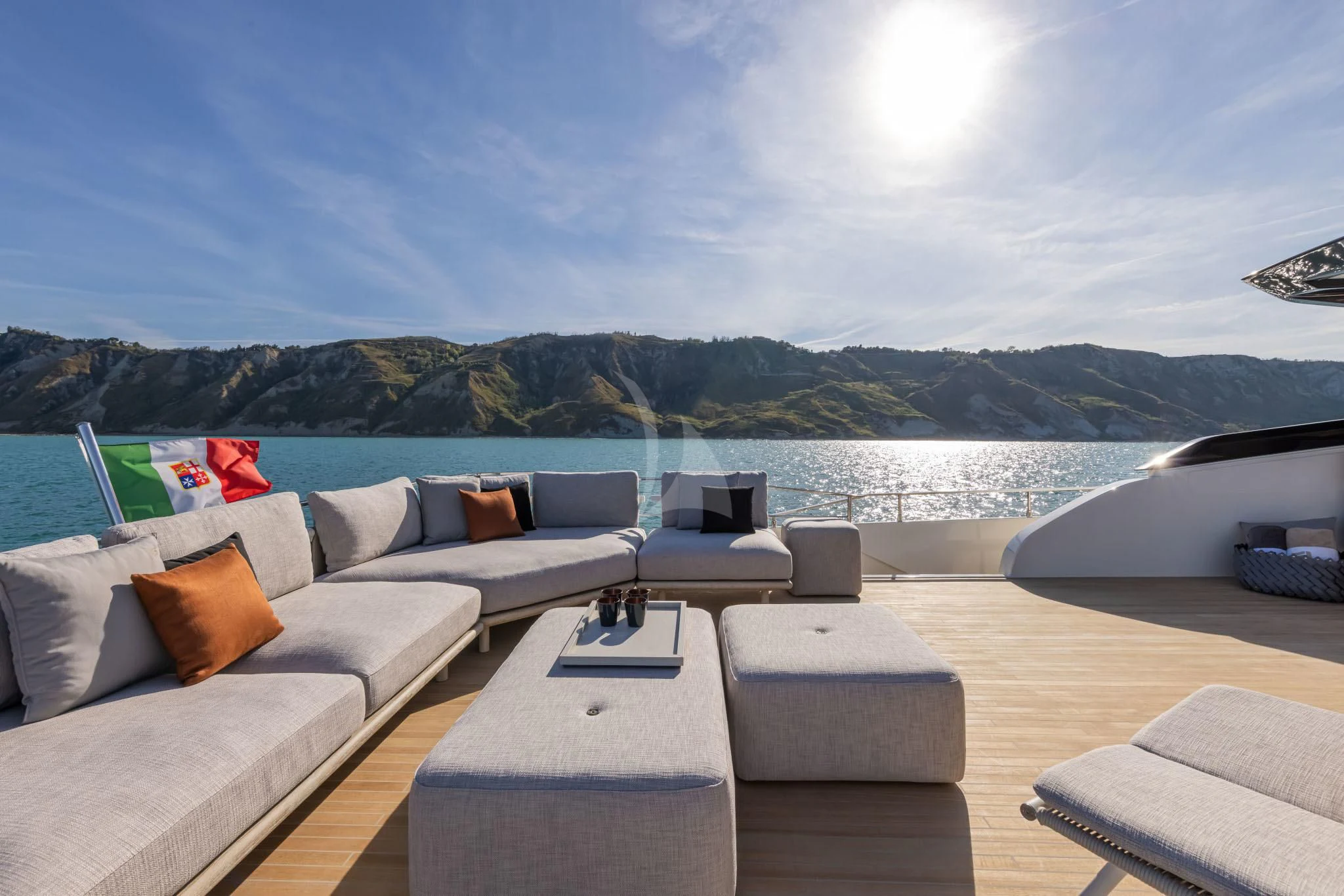 a deck with a view of a body of water and mountains in the background aboard H&CO Yacht for Sale