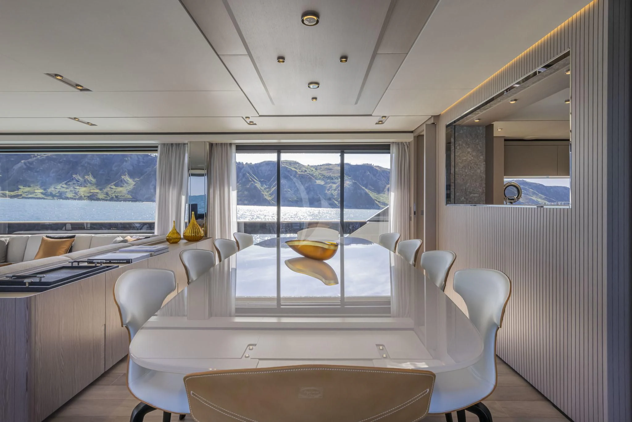 a room with a large window and a table with chairs and a view of the ocean aboard H&CO Yacht for Sale