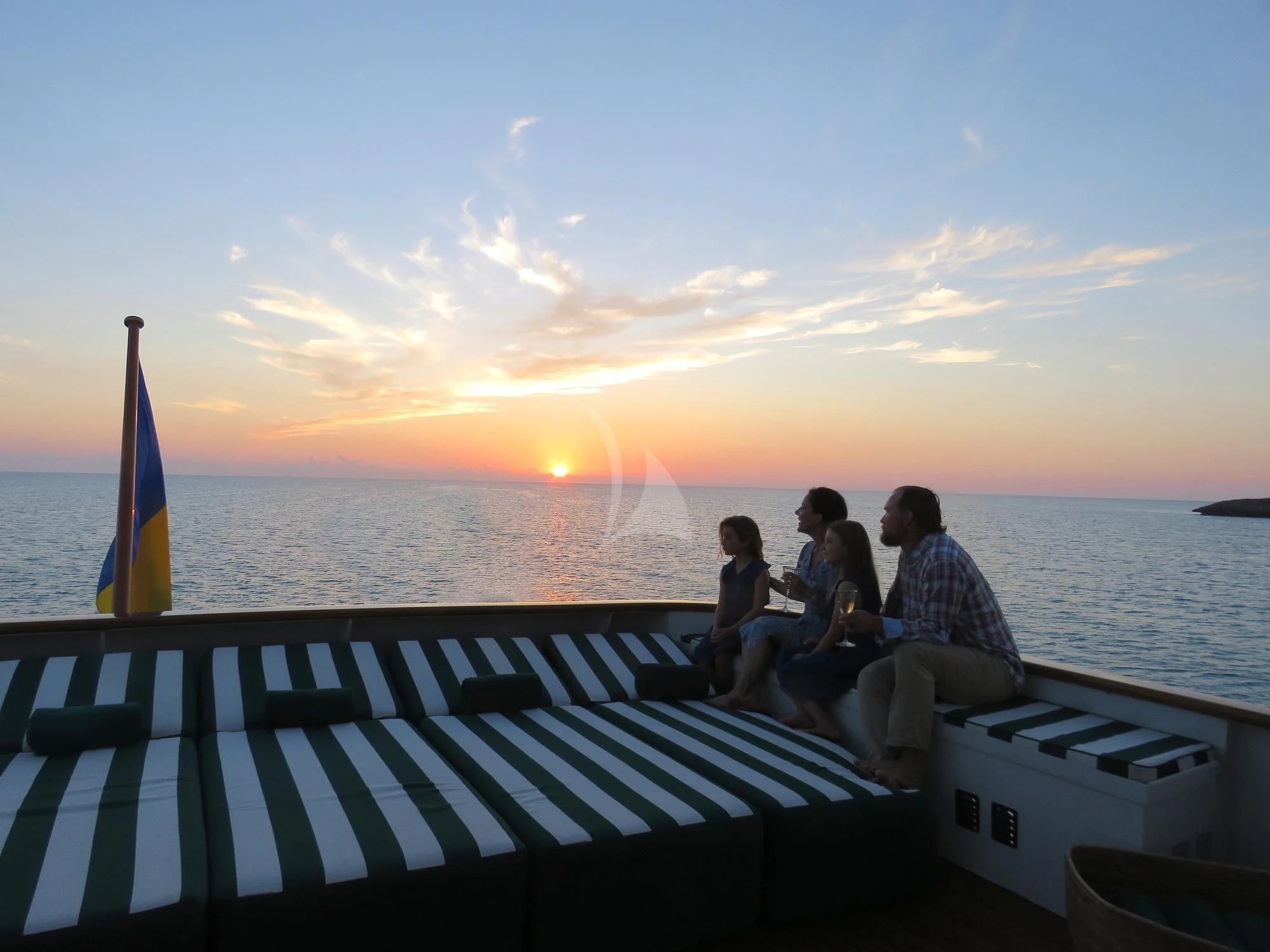 a group of people sitting on a dock with a sunset in the background aboard BIG EAGLE Yacht for Sale