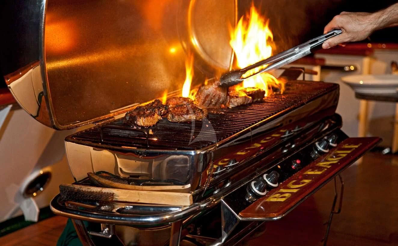 a grill with meat and flames aboard BIG EAGLE Yacht for Sale
