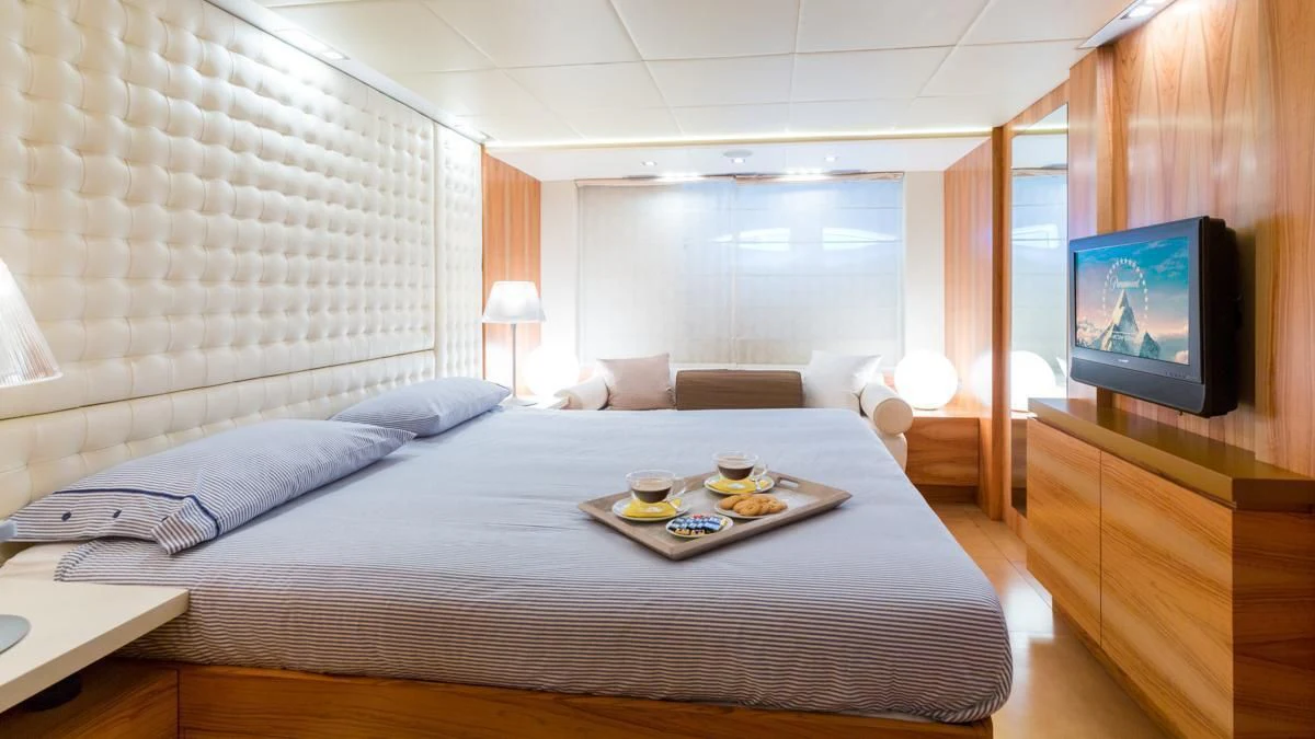 a bed room with a tv and a table aboard BLUE DEVIL Yacht for Sale