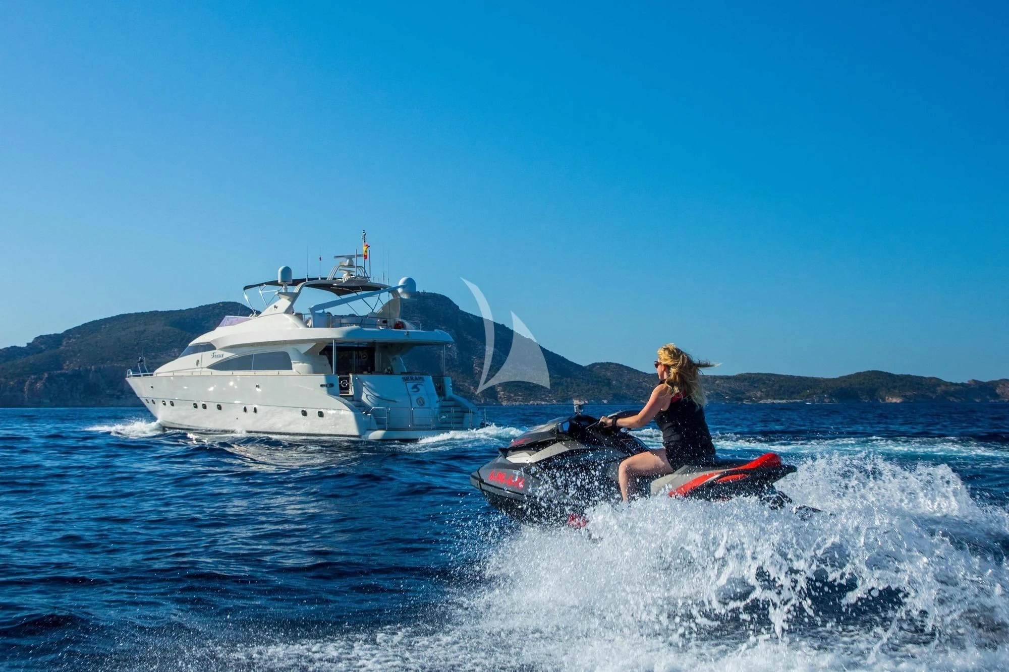 a man on a surfboard in the water next to a boat aboard SERAPH PRIMERO Yacht for Sale