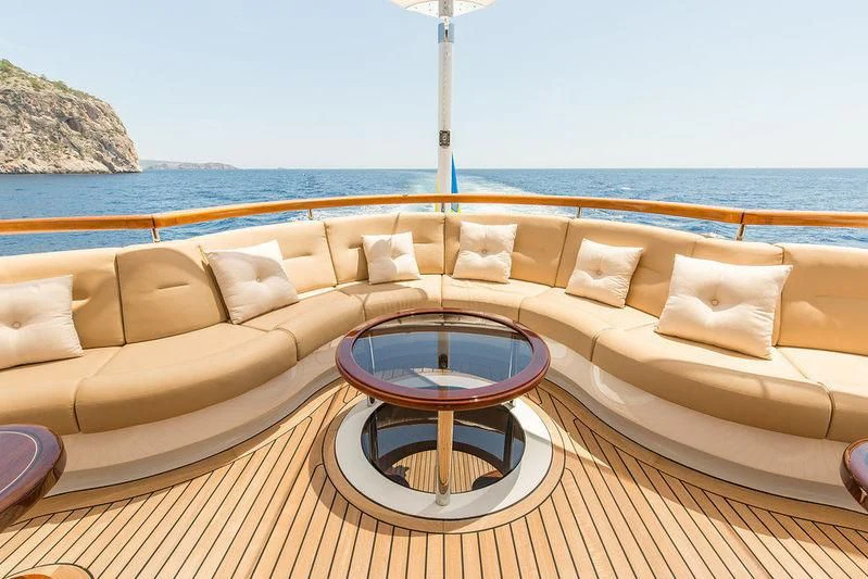 a couch and a table on a deck overlooking a beach aboard VITA NOVA Yacht for Sale