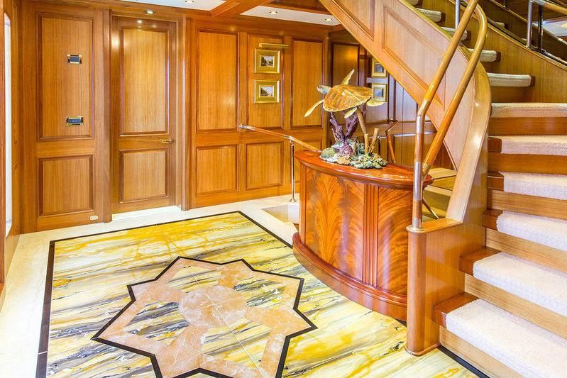 a room with a staircase and a table with a vase on it aboard VITA NOVA Yacht for Sale