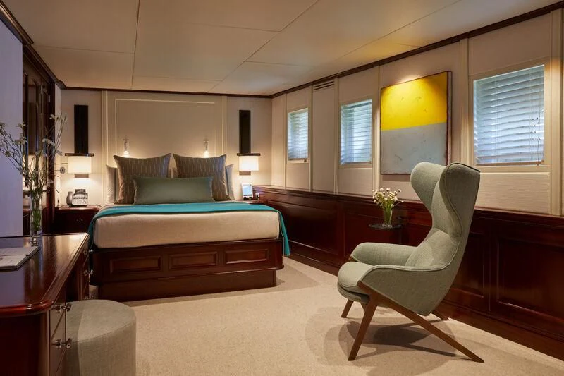 a bedroom with a bed and a chair aboard JUST B Yacht for Sale