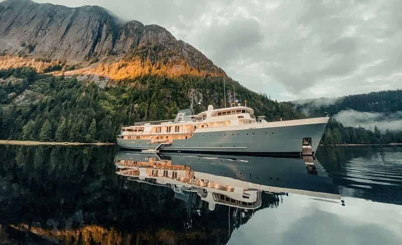 a large ship in a body of water with mountains in the background aboard JUST B Yacht for Sale