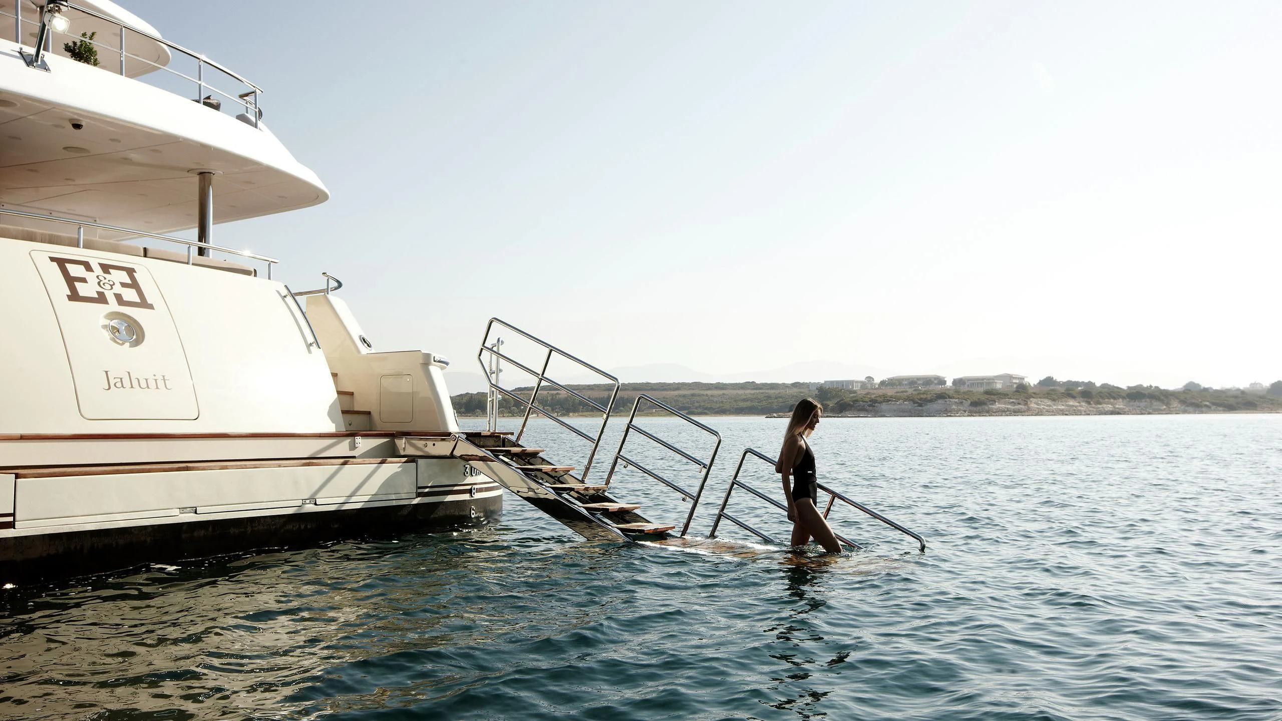 a man on a paddle board next to a boat aboard E&E Yacht for Sale