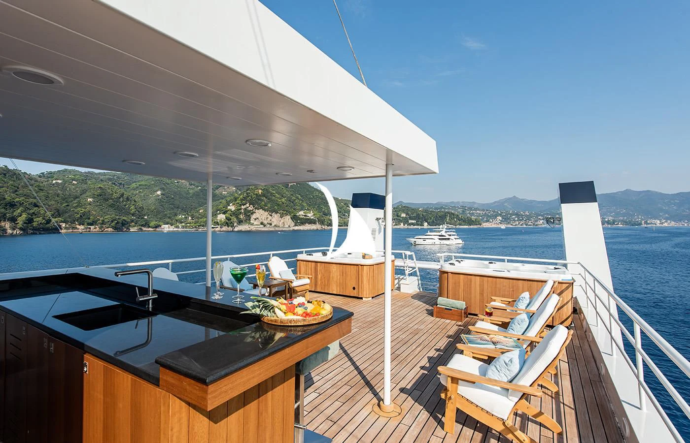 a deck with a table and chairs on it and a boat on the water aboard BLEU DE NIMES Yacht for Charter