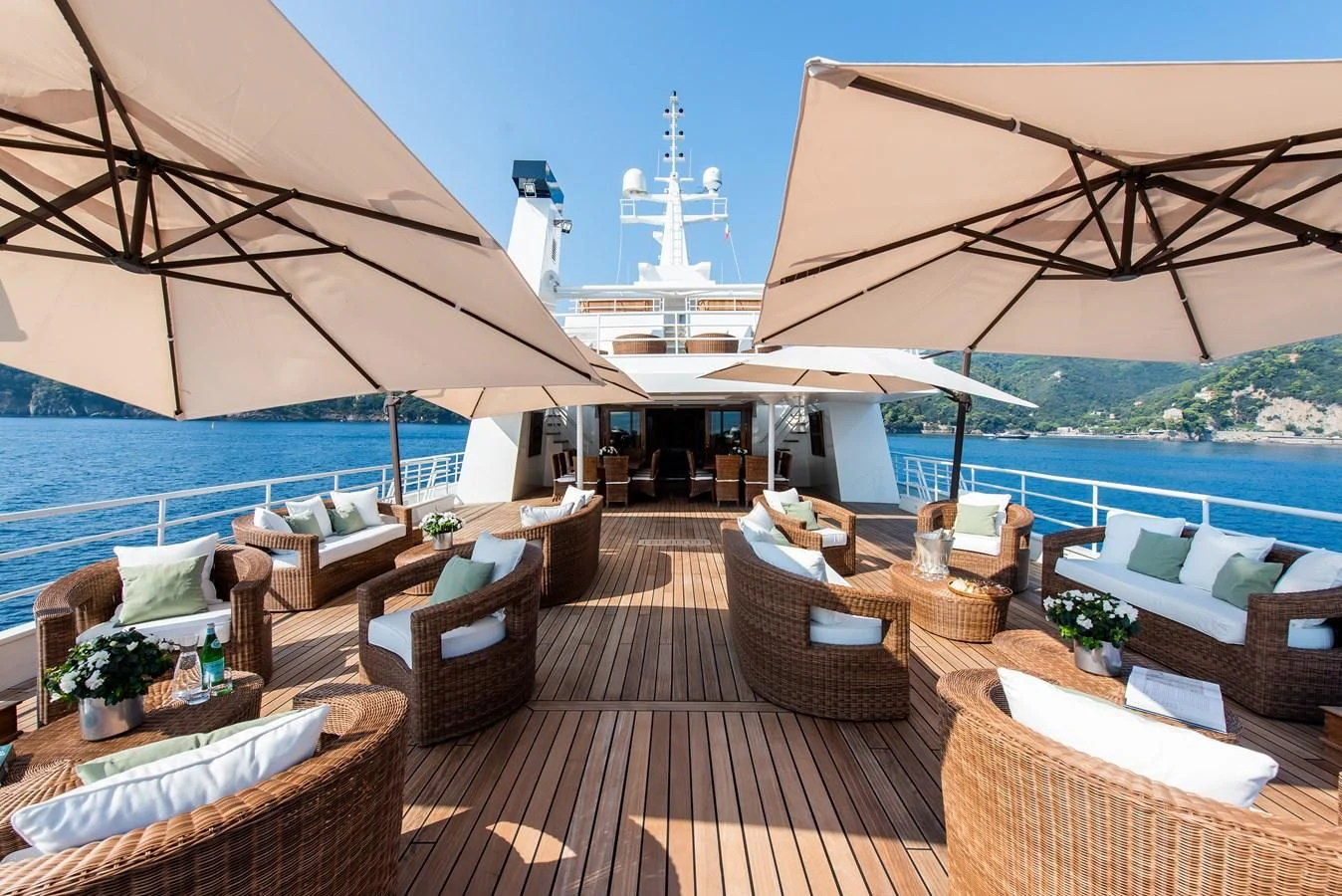 a deck with chairs and tables on it by a body of water aboard BLEU DE NIMES Yacht for Charter