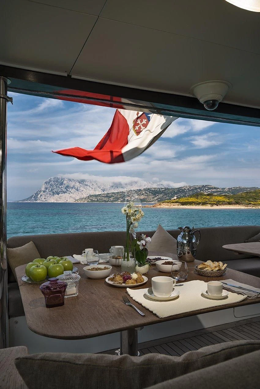 a table with food and drinks on it by a window with a view of the mountains aboard INDIAN Yacht for Sale