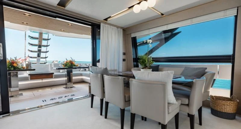 a room with white chairs and a table with a large window aboard BASH II Yacht for Sale