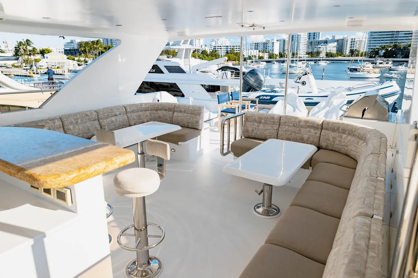 a room with a couch and a table with chairs and a city in the background aboard HAPPY Yacht for Sale