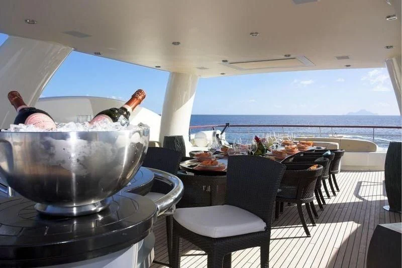 a person pouring a drink into a glass on a table aboard DENIKI Yacht for Sale