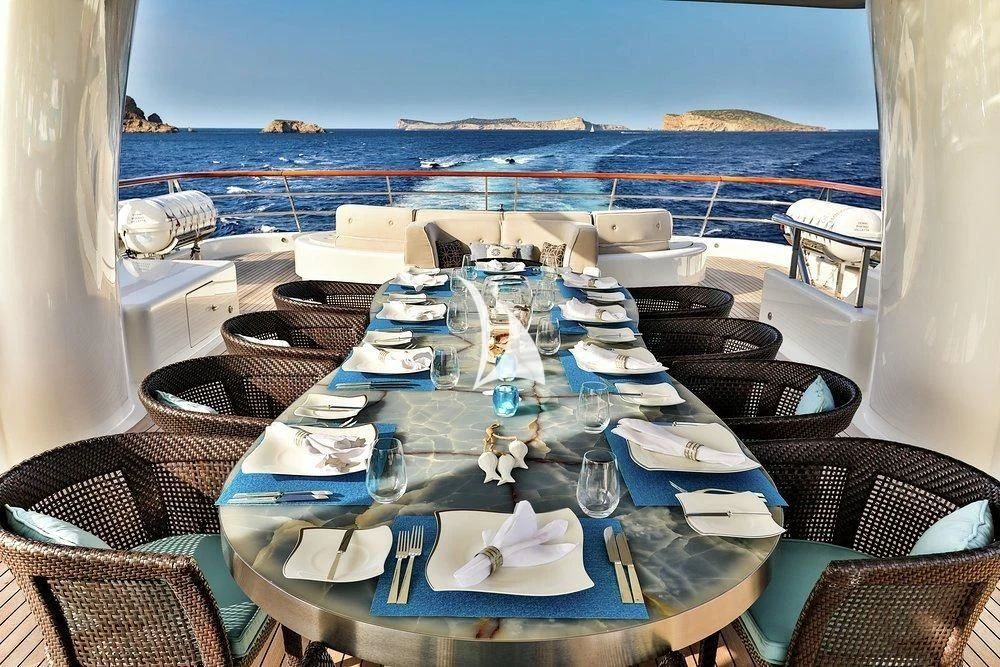 a table set for a meal on a balcony overlooking the ocean aboard DENIKI Yacht for Sale