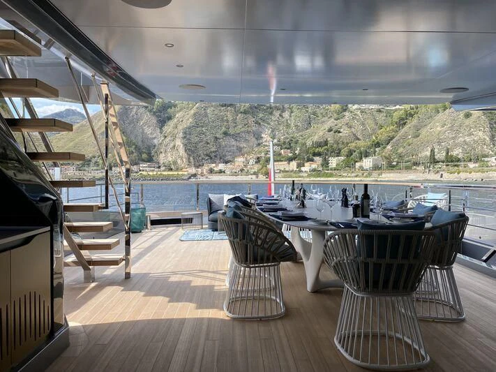 a deck with a table and chairs on it aboard PANDION PEARL Yacht for Charter