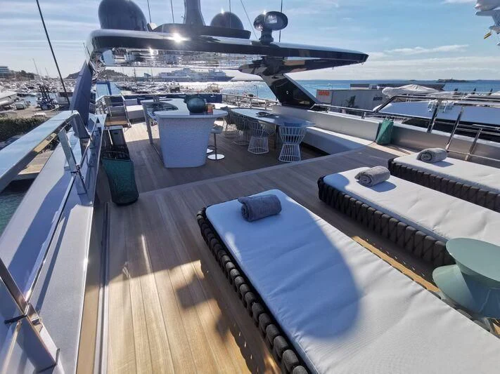 a deck with a deck and a large ship in the background aboard PANDION PEARL Yacht for Charter