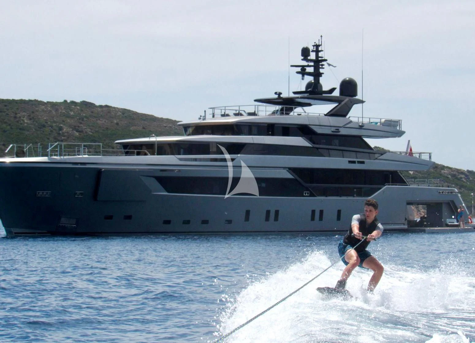 a man water skiing in front of a large ship aboard PANDION PEARL Yacht for Charter