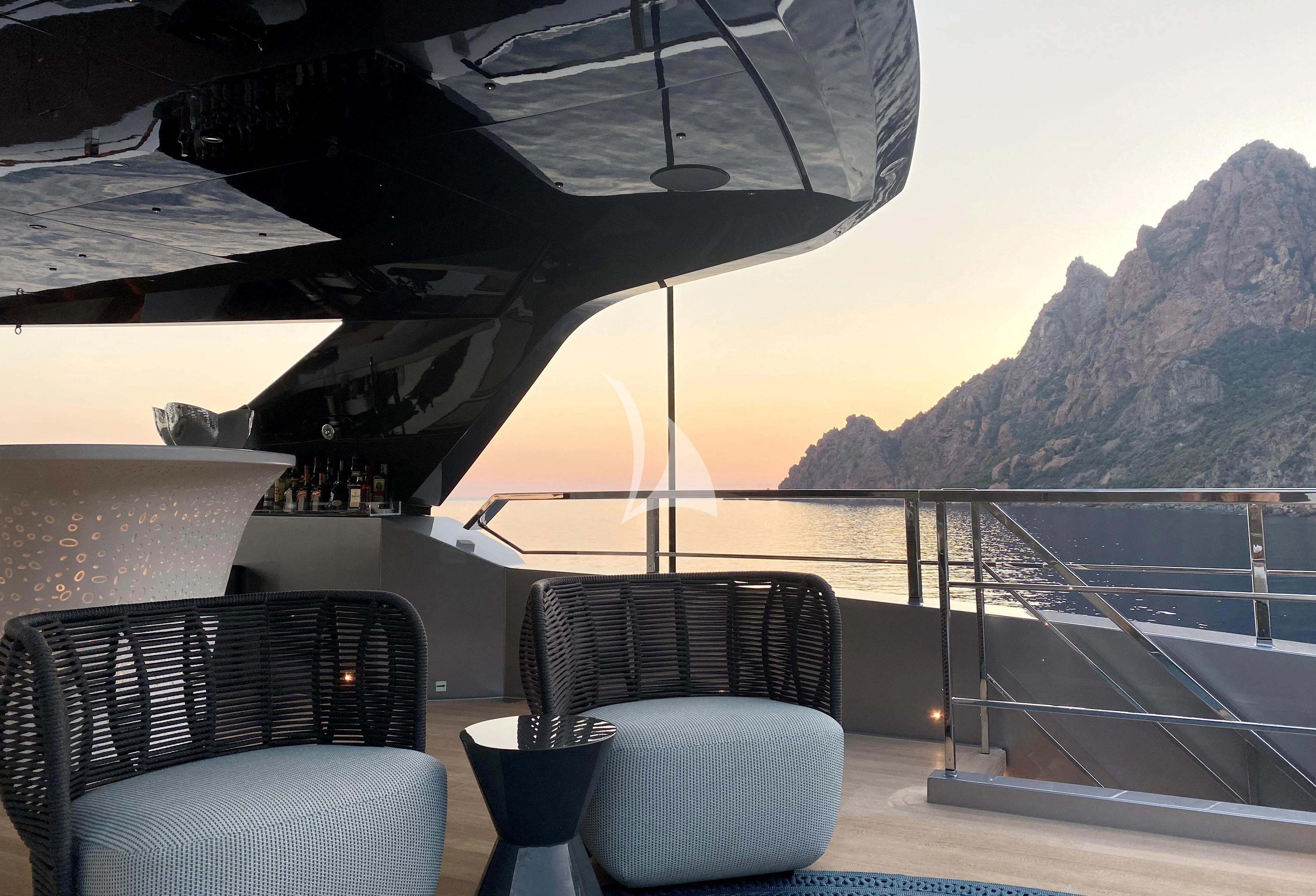 a patio with chairs and a railing overlooking a body of water aboard PANDION PEARL Yacht for Charter