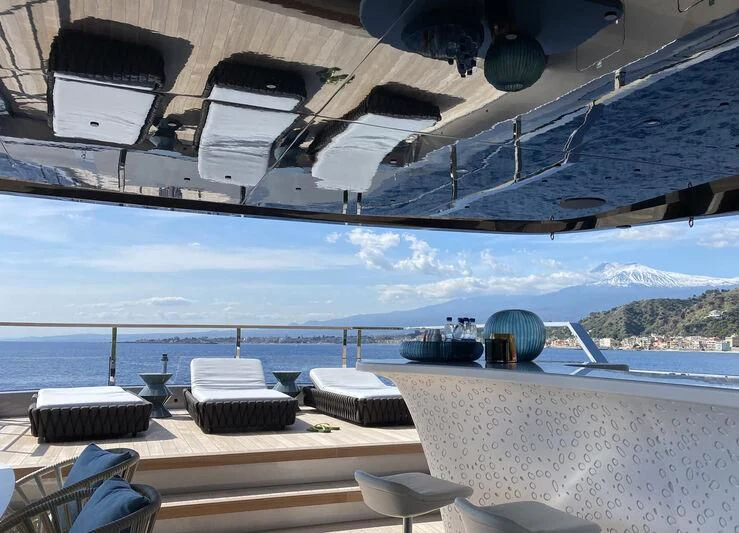 a room with a view of the ocean and a large ship aboard PANDION PEARL Yacht for Charter