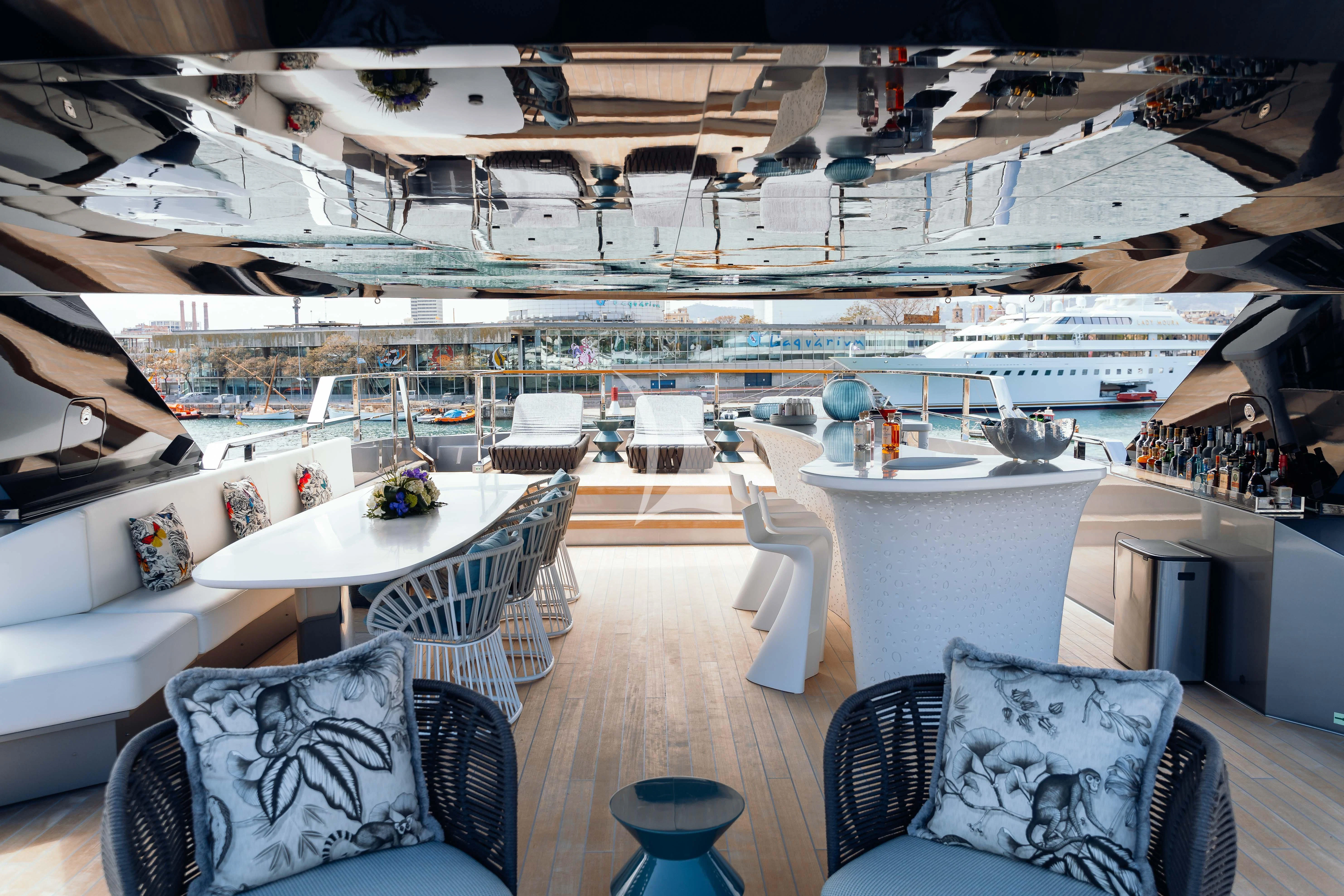 a room with a table chairs and a large white boat in the background aboard PANDION PEARL Yacht for Charter