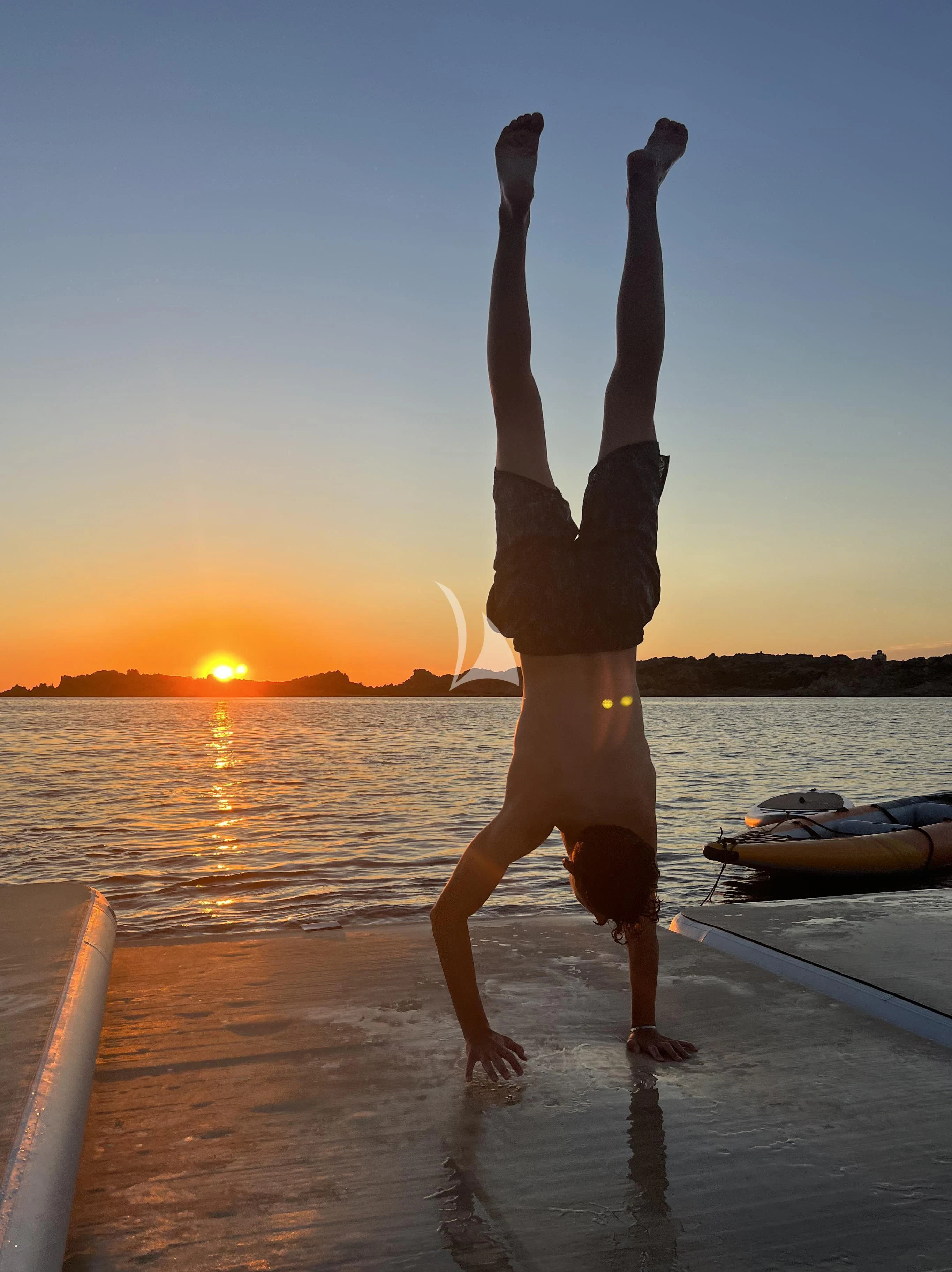 a person doing a handstand on a dock at sunset aboard PANDION PEARL Yacht for Charter