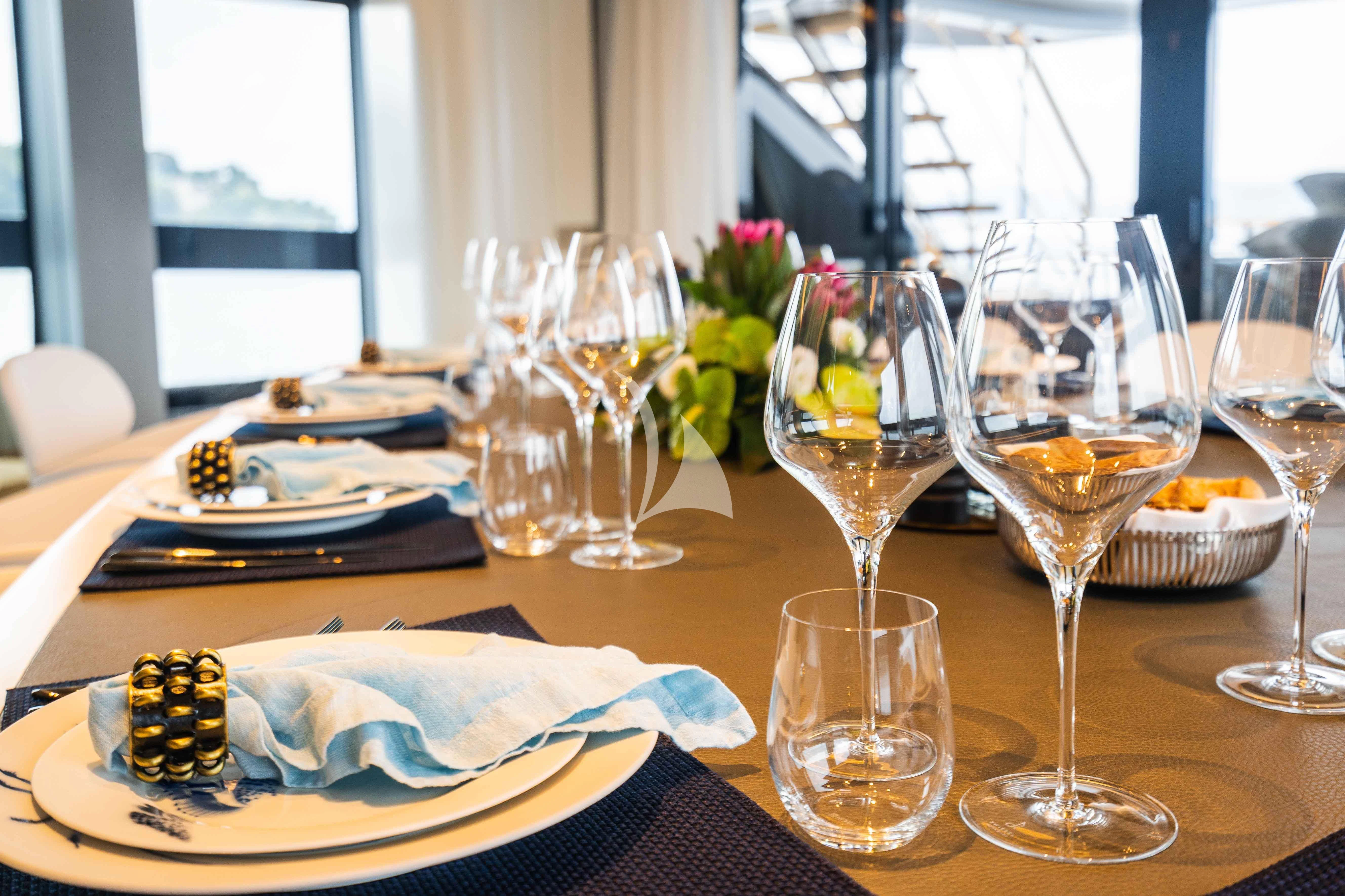 a table with wine glasses and plates aboard PANDION PEARL Yacht for Charter