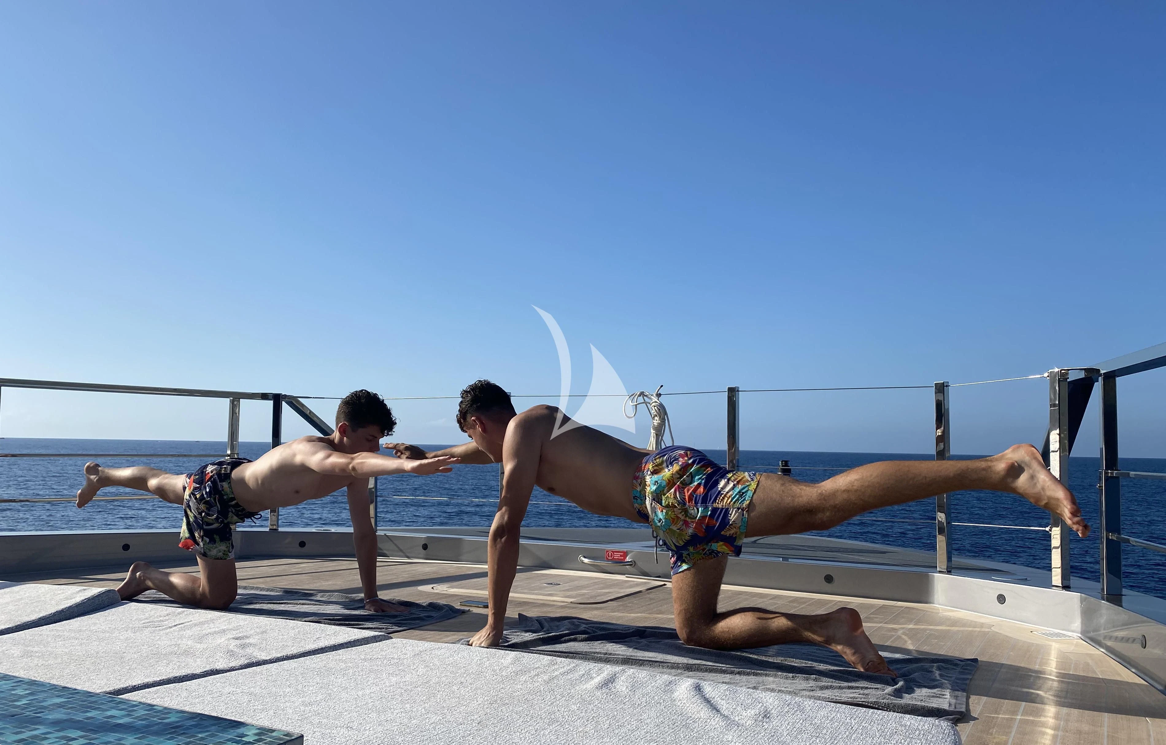 a group of men doing a handstand on a dock aboard PANDION PEARL Yacht for Charter