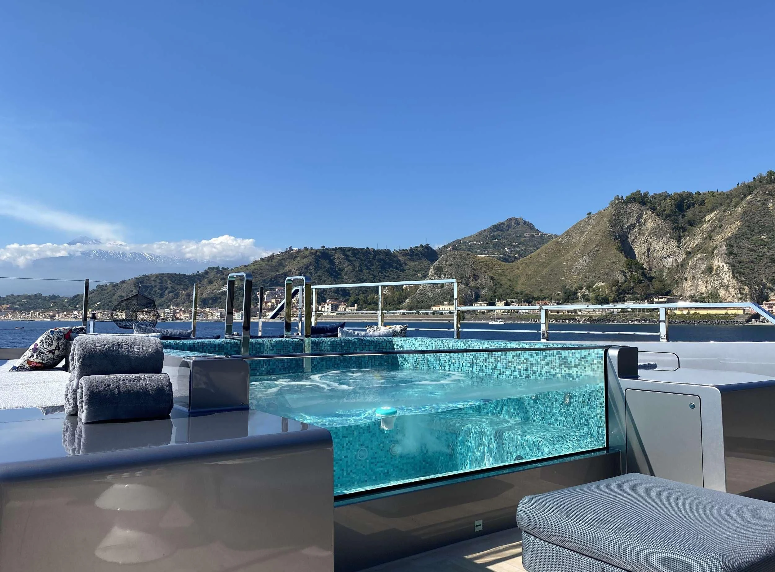 a pool with a deck and a view of mountains and water aboard PANDION PEARL Yacht for Charter