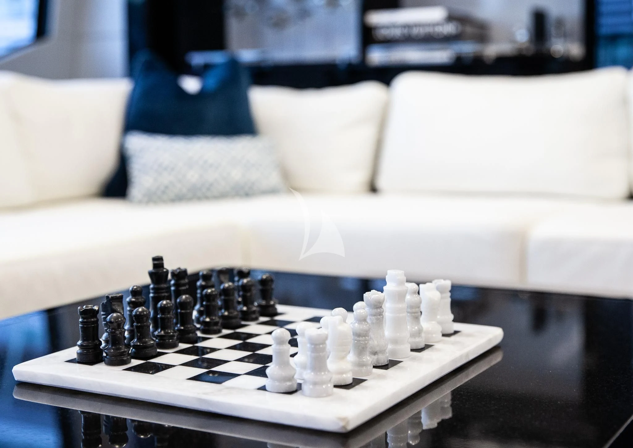 a white table with a white couch and white chess pieces on it aboard SONISHI Yacht for Sale