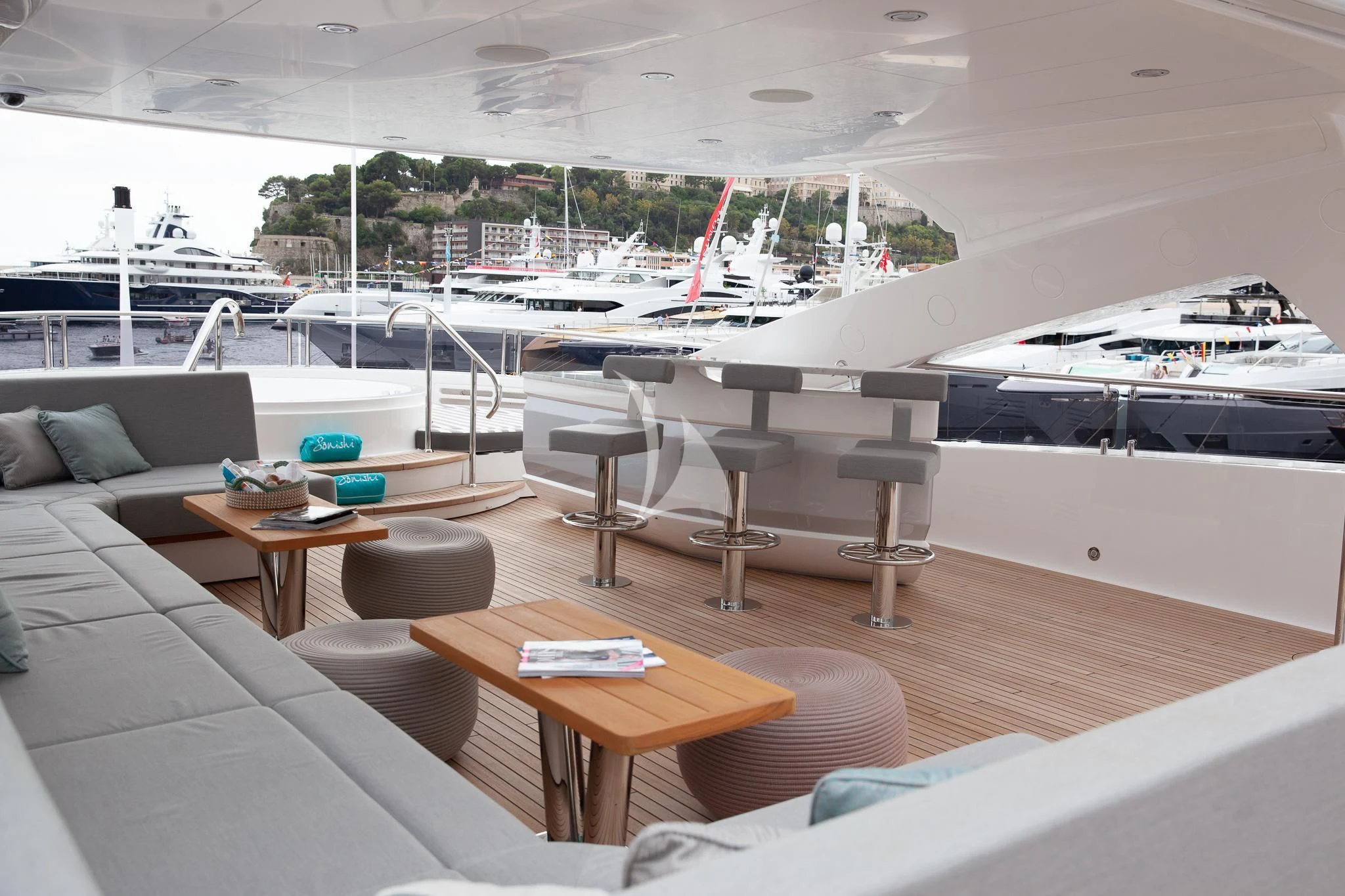 a room with a couch and a table with chairs and a table with boats in the background aboard SONISHI Yacht for Sale