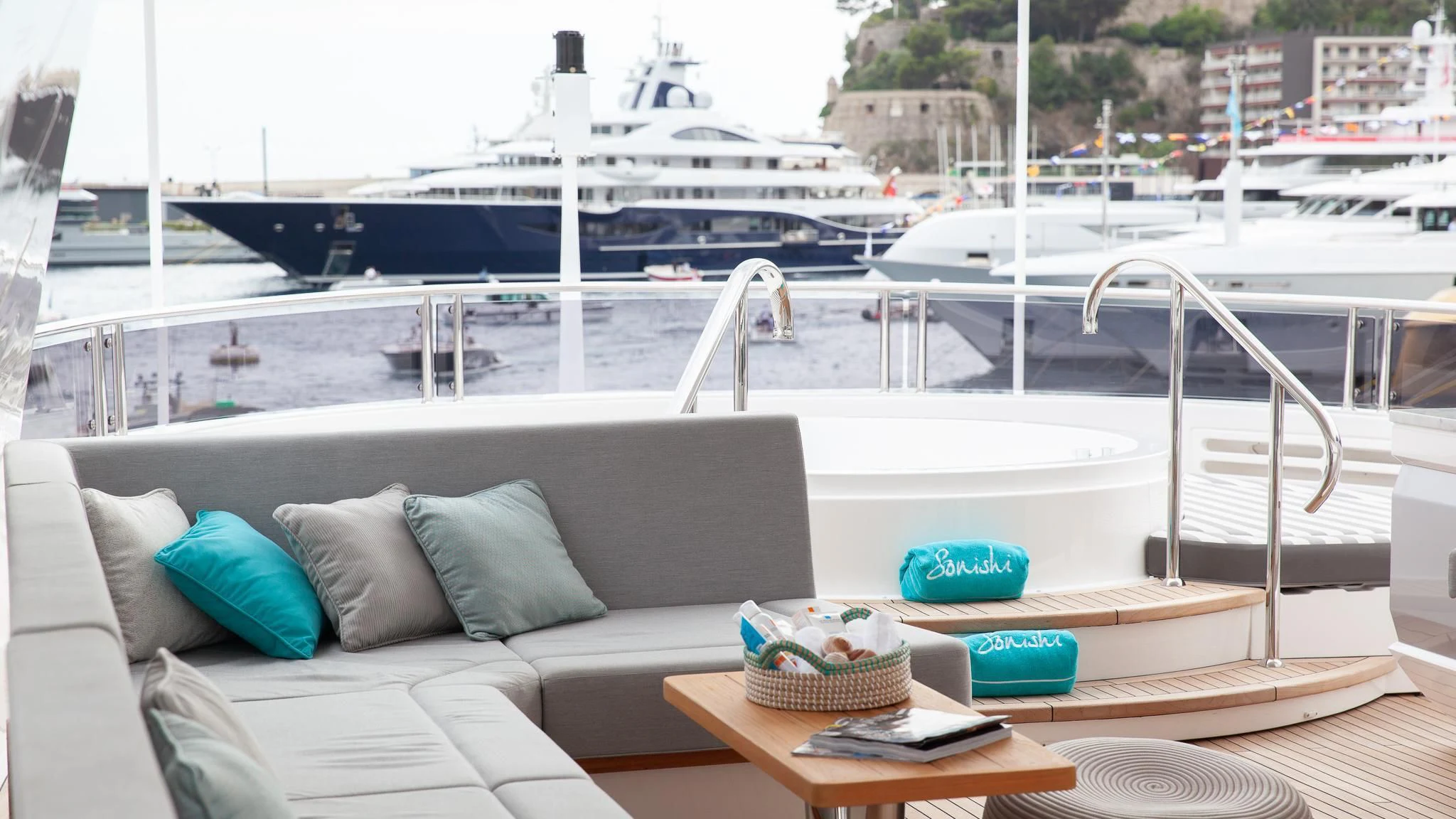 a table with a bowl of fruit on it by a window with a ship in the background aboard SONISHI Yacht for Sale