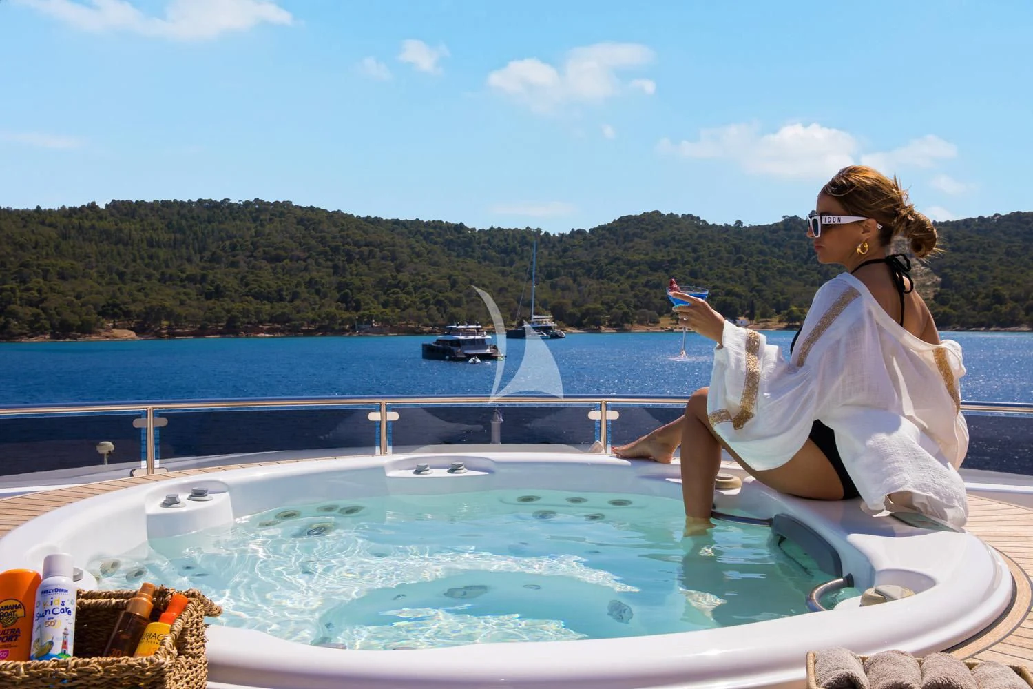 a person sitting on a chair at a table by a pool aboard PERSEFONI I Yacht for Sale