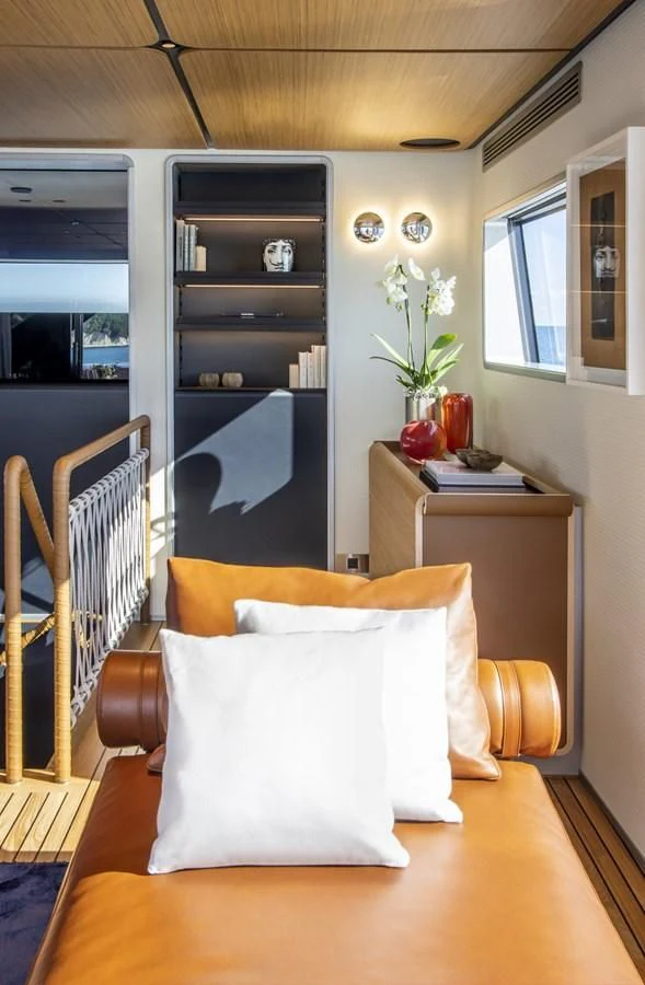 a room with a chair and a table and a shelf with objects on it aboard UPSTREAM Yacht for Sale
