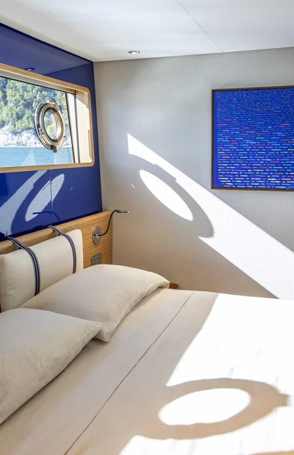 a bed with a painting on the wall aboard UPSTREAM Yacht for Sale