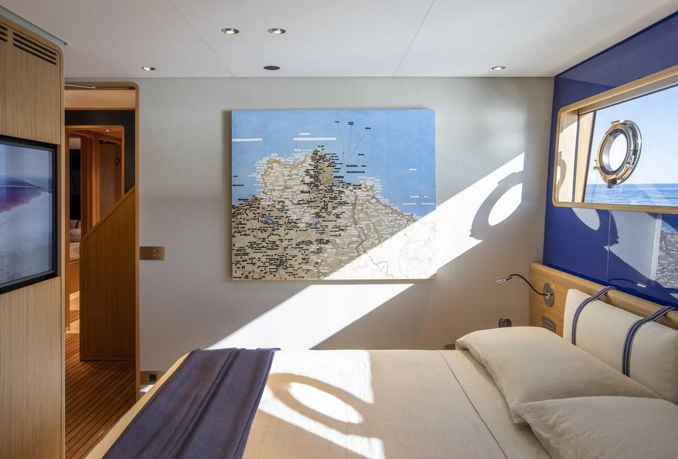 a bed with a blue wall and a painting on the wall aboard UPSTREAM Yacht for Sale