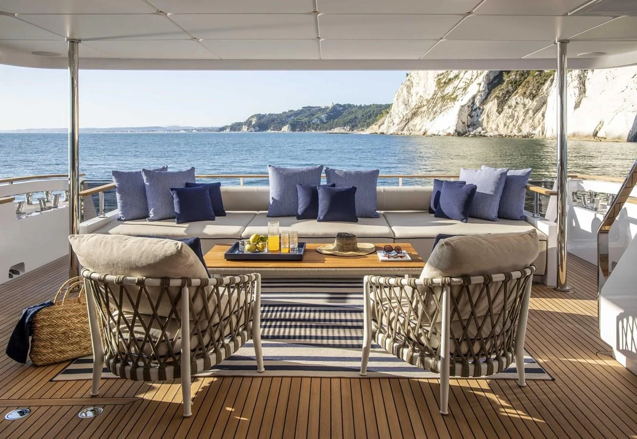 a large white couch sits on a wood table aboard UPSTREAM Yacht for Sale