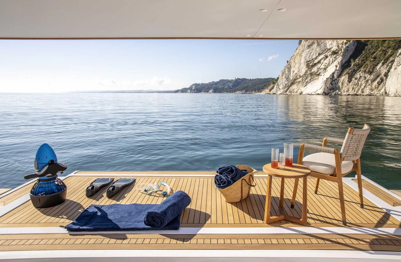 a table and chairs on a deck by a body of water aboard UPSTREAM Yacht for Sale