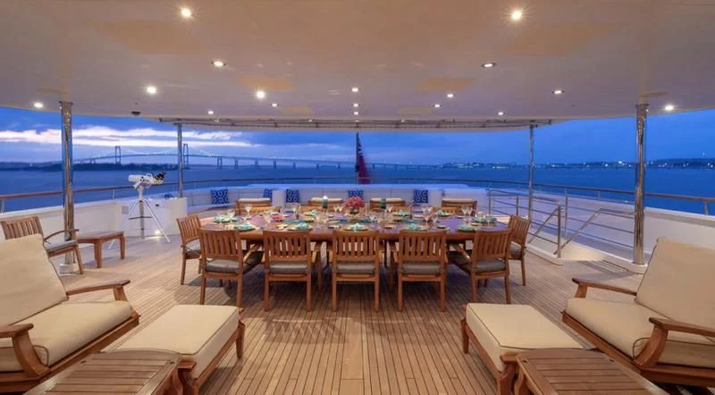 a large room with a table and chairs and a large body of water aboard LAUREL Yacht for Charter