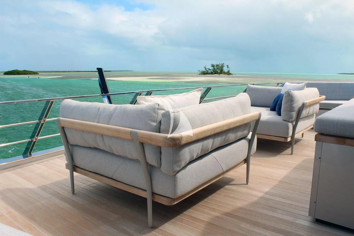 a couch and a table on a deck overlooking a body of water aboard BAD MUTHA Yacht for Sale