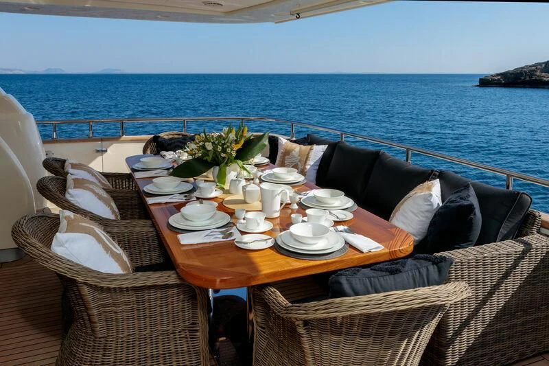 a table with plates and chairs on it next to a body of water aboard MIRAVAL Yacht for Charter