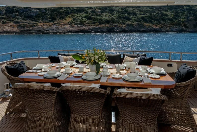 a table set with plates and cups on a patio overlooking a body of water aboard MIRAVAL Yacht for Charter