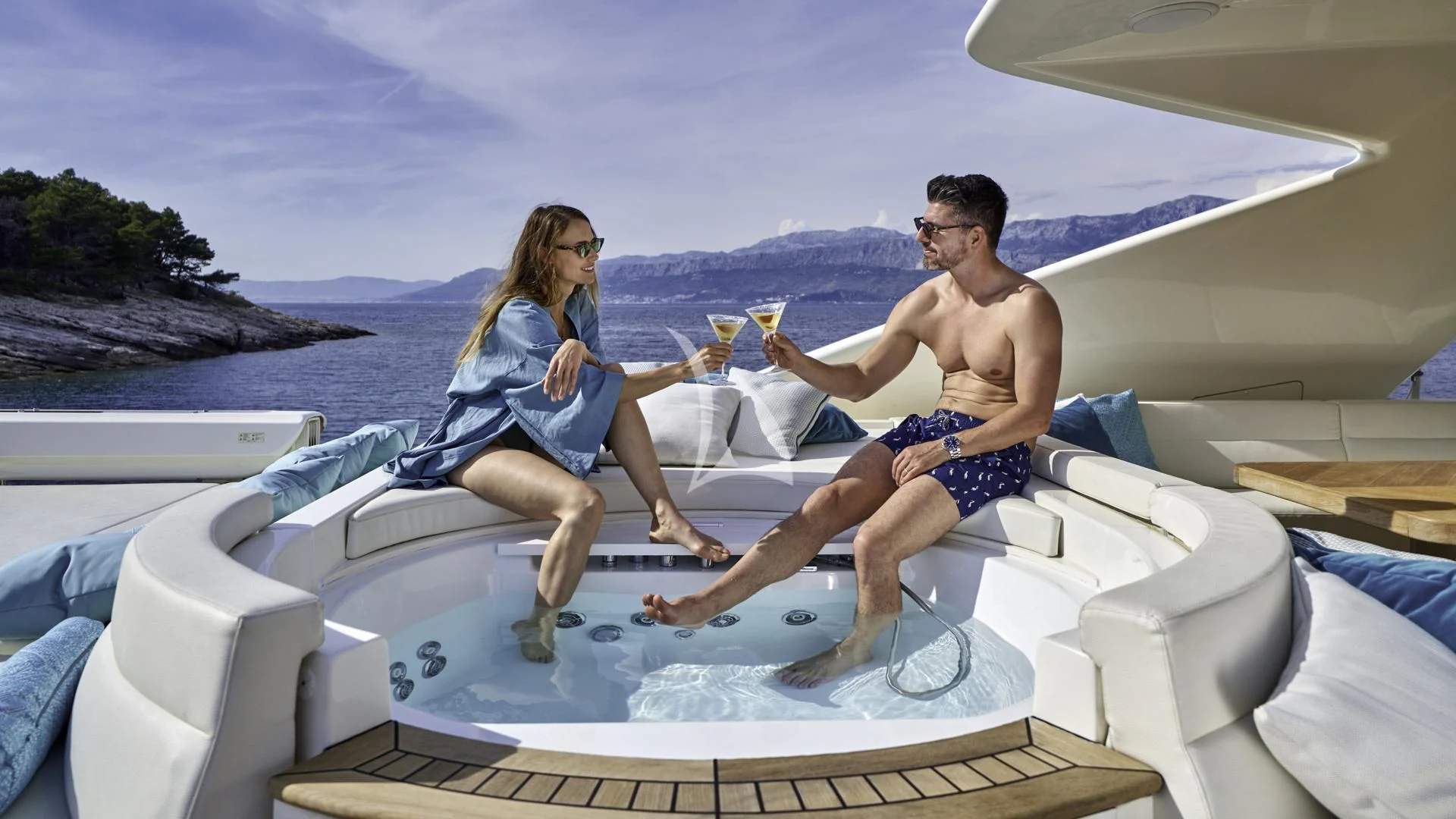a man and woman sitting on a white couch eating ice cream aboard ACCEPTUS Yacht for Sale