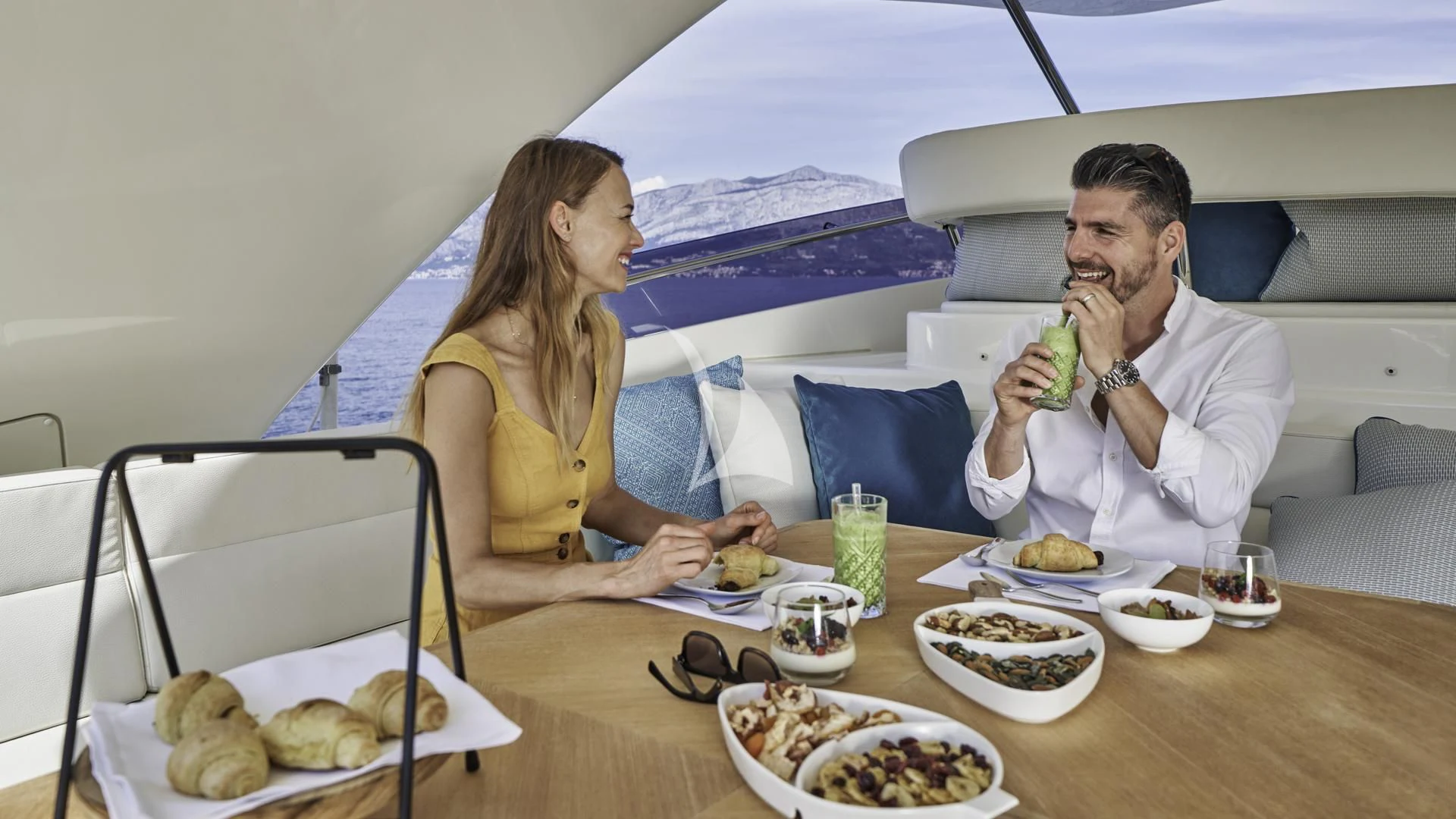 a man and woman sitting at a table with food and drinks aboard ACCEPTUS Yacht for Sale