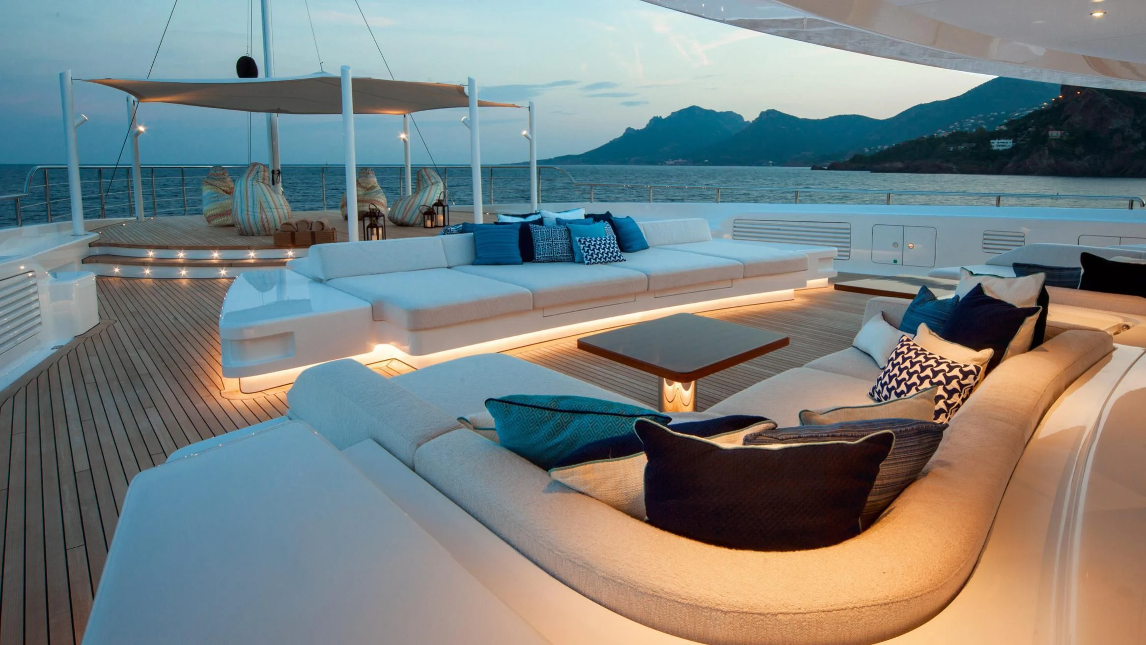 a large lounge area with a large body of water and mountains in the background aboard STARBURST IV Yacht for Charter